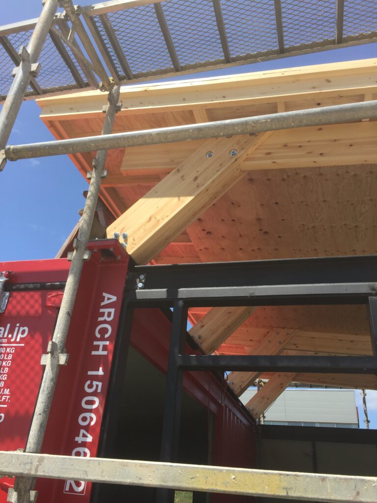 木造の屋根がコンテナハウスの上にかかります