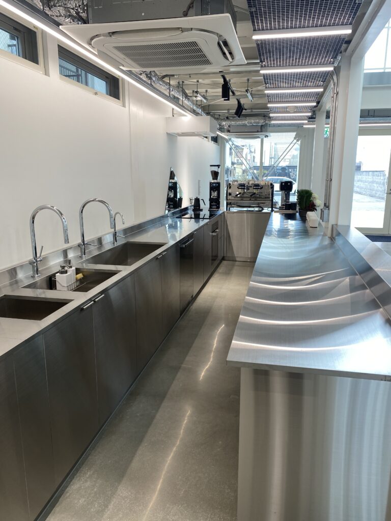 IMG_1713 | コンテナハウスのことなら_現代コンテナ建築研究所 ステンレスカウンターが光を反射する工業的内装、コンテナ建築の厨房・CAFE空間